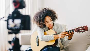 Eine junge Frau streamt eine Gitarrenstunde