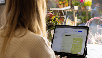 Florist creating her business website with Jimdo on a laptop in a flower shop — simple website building made easy.